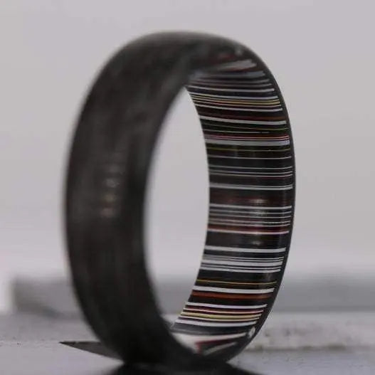 Mens wedding ring made from fordite and carbon fibre material with glow powder